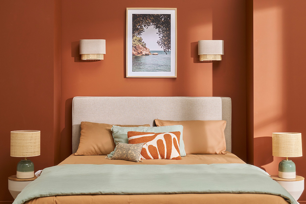 Chambre avec deux appliques murales en lin beige et rotin au-dessus du lit avec coussins color�s.