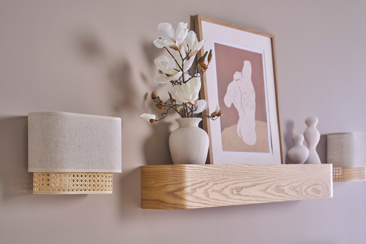 Applique murale en lin beige et cannage rotin sur mur, �tag�re avec vase et cadres.