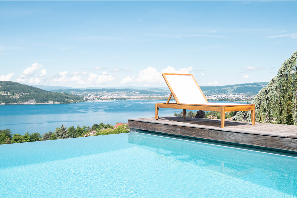 Bain de soleil blanc et bois massif NAVEEN pr�s d'une piscine avec vue lac et montagnes.