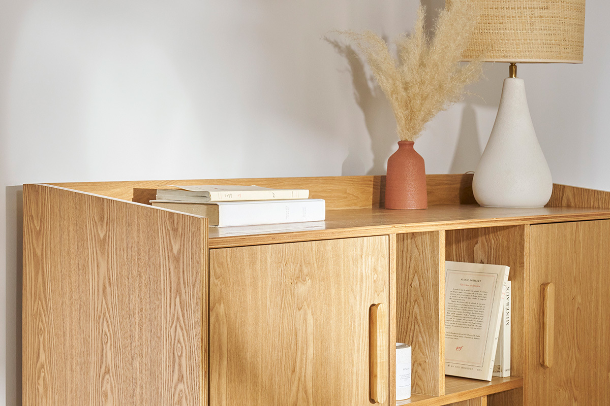 Buffet scandinave en bois clair avec �tag�res, livres et d�co sur le dessus, vue de c�t�.