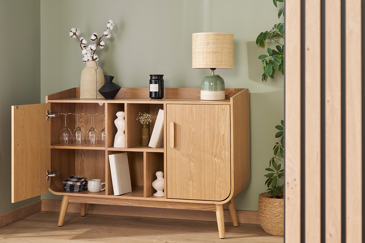 Buffet scandinave en bois clair, une porte ouverte, �tag�res visibles, d�cor� de livres et objets.
