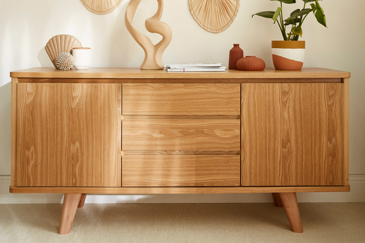 Buffet scandinave en bois clair avec 2 portes et 3 tiroirs, d�cor� de plantes et objets sur le plateau.