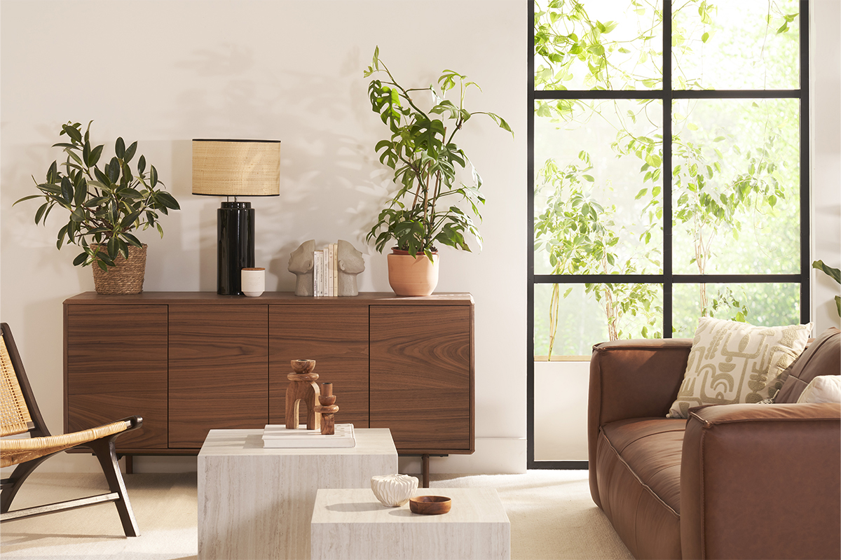 Buffet vintage en bois fonc� noyer SUVA, 4 portes, d�cor� de plantes et d'une lampe, dans un salon lumineux.