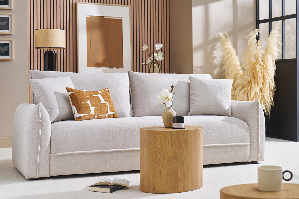 Canap� 3 places beige en tissu effet velours avec coussins, vue de face, avec une table basse ronde.