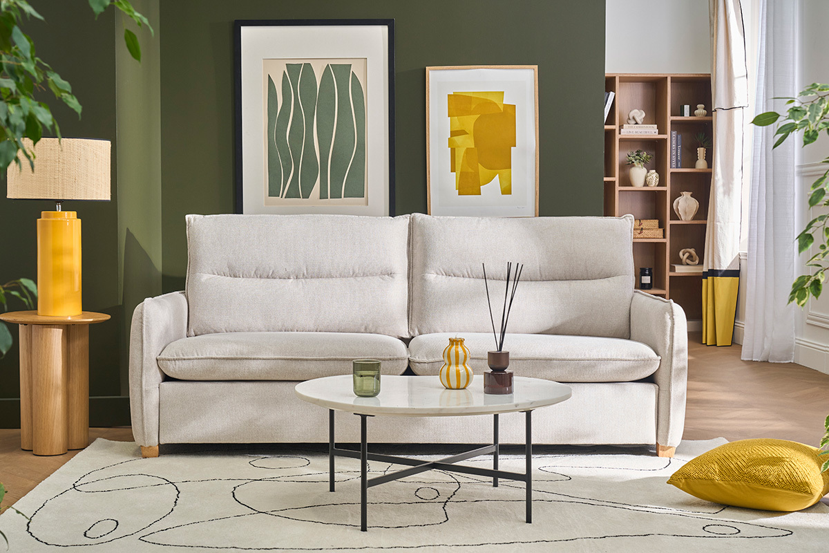 Canap� 3 places beige effet velours, vue de face, avec table basse et d�coration int�rieure.