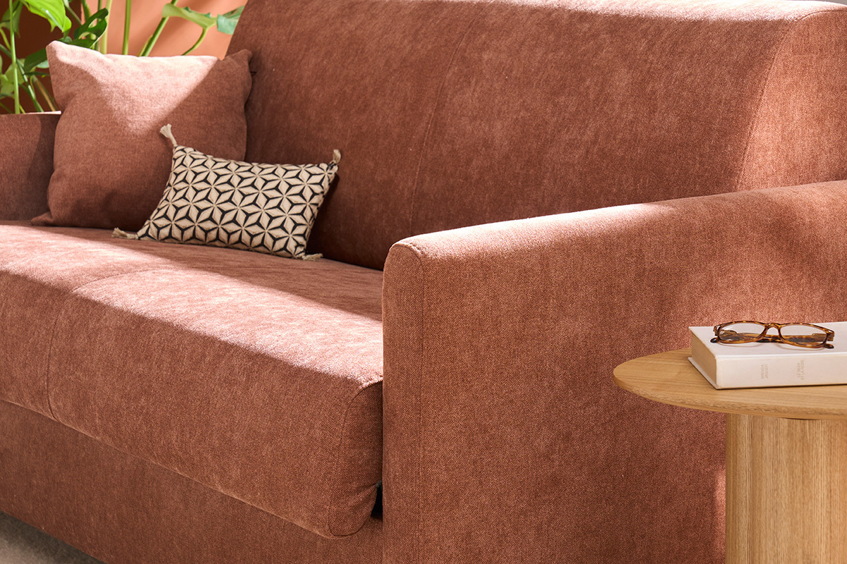 Canap� convertible en velours terre br�l�e, accoudoir droit et coussins avec petite table en bois.