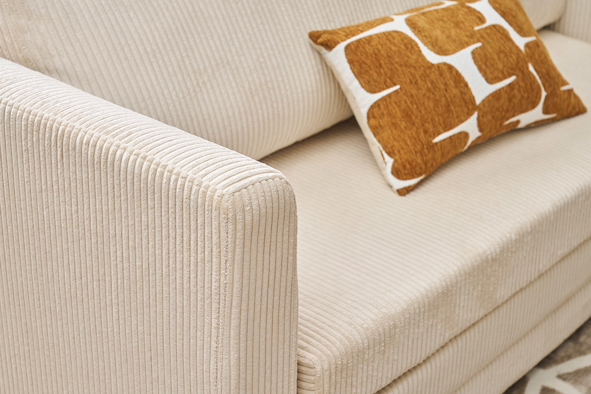 D�tail du canap� convertible LEON en tissu velours c�tel� beige avec un coussin d�coratif.