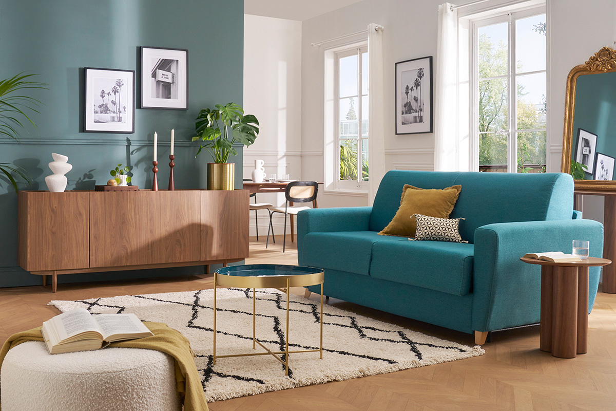 Canap� convertible 3 places bleu canard avec coussins, table basse et d�cor scandinave, vue de face.