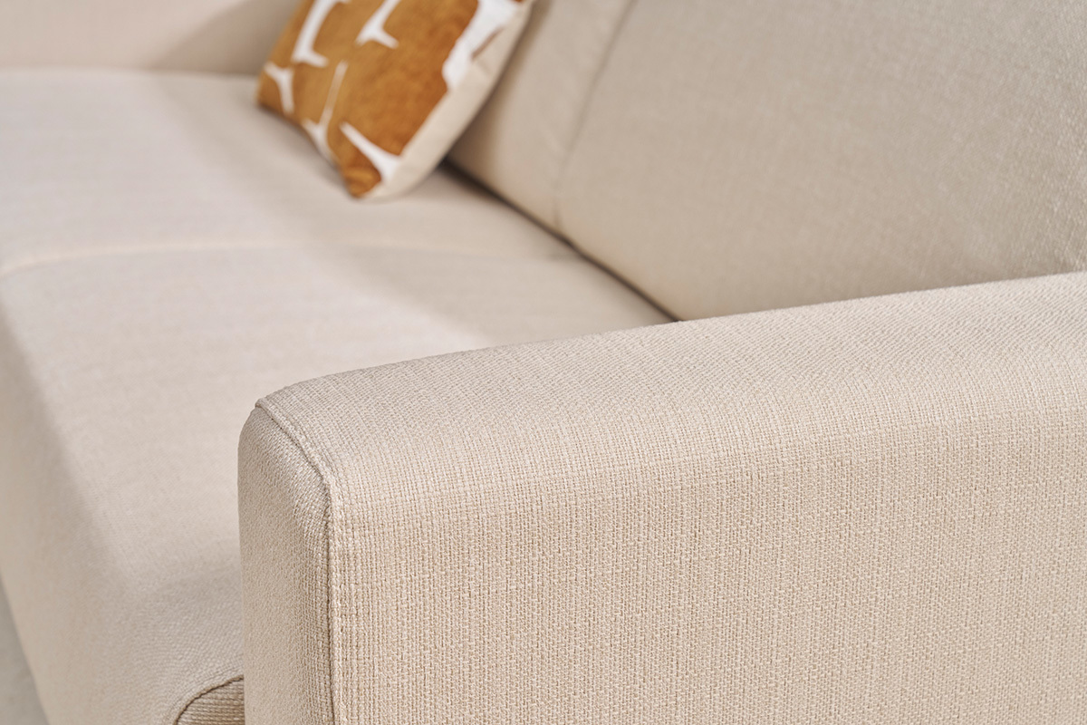 Accoudoir d'un canap� beige en tissu avec coussin d�coratif. Vue en gros plan.