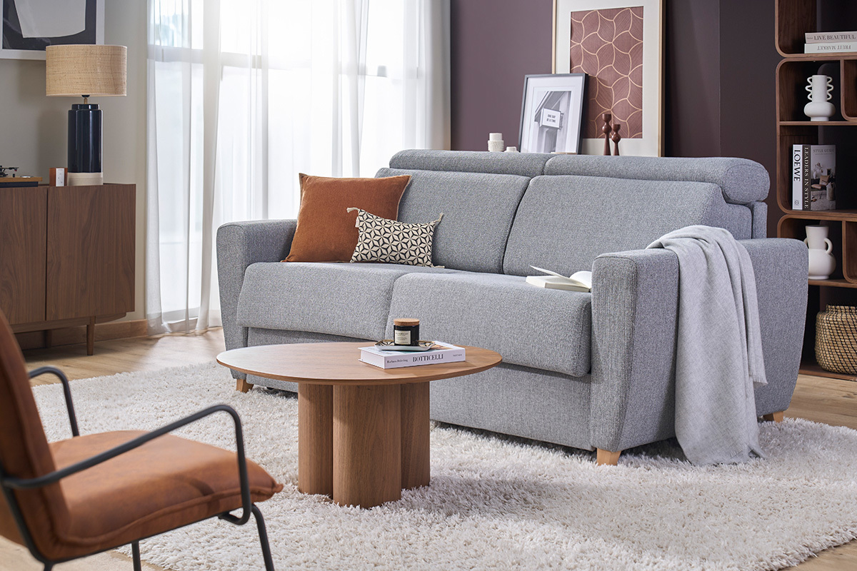Canap� convertible 3 places gris avec t�ti�res ajustables, vue de 3/4 dans un salon moderne