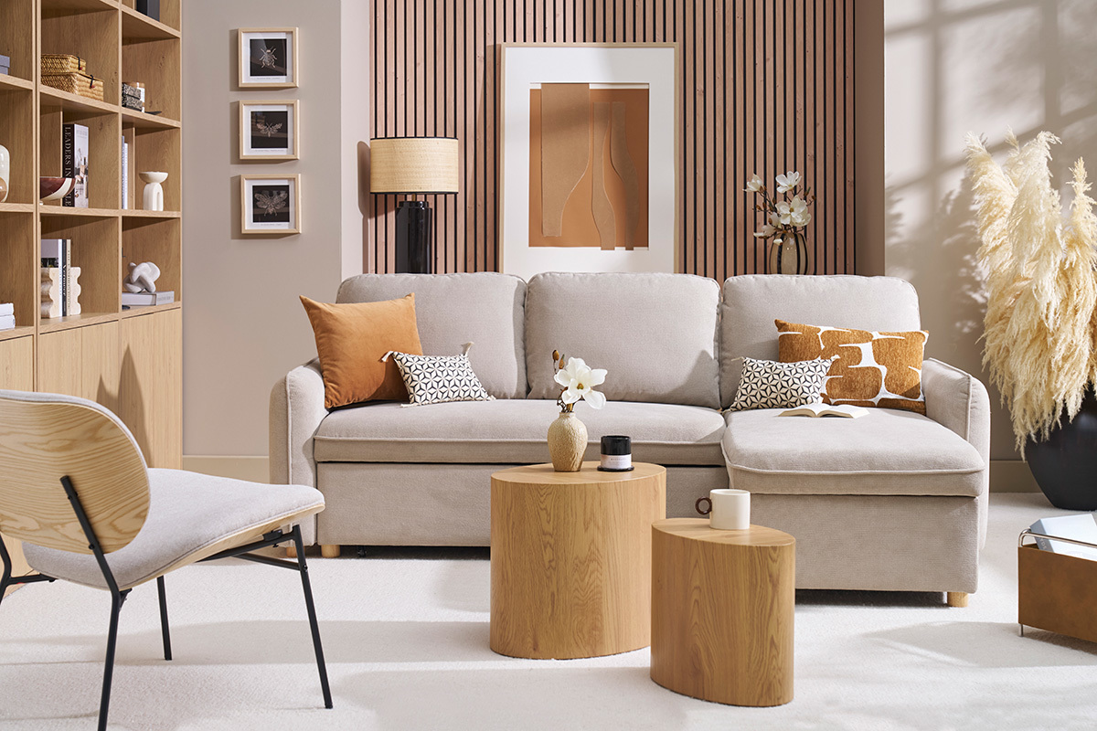 Canap� d'angle convertible beige avec coussins, tables basses en bois et fauteuil.