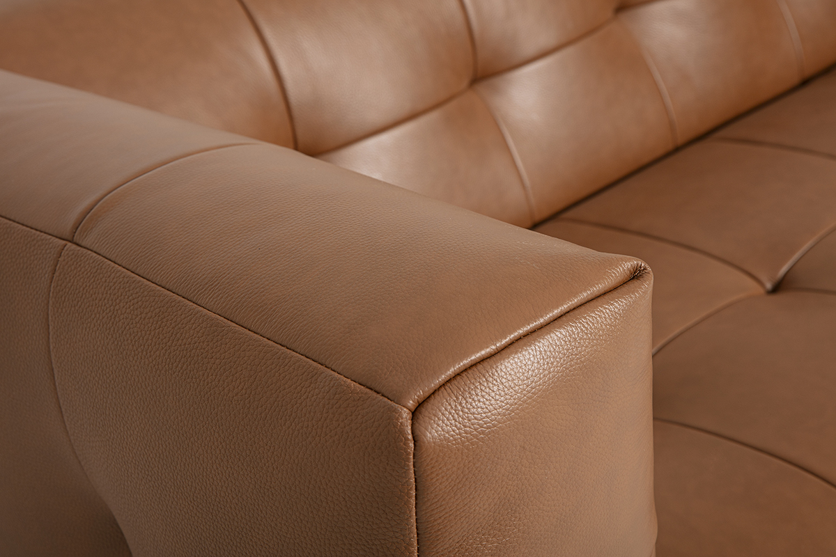 D�tail d'un canap� en cuir marron avec accoudoir et coussin visible.