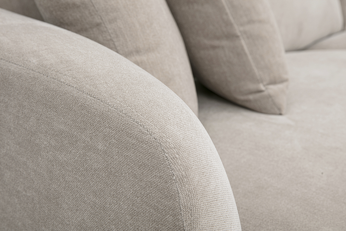 D�tail du canap� design 3 places en tissu taupe, avec accoudoirs arrondis et coussins moelleux.