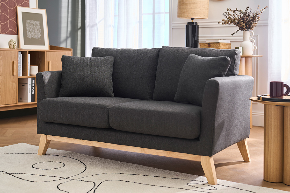 Canap� 2 places en tissu gris fonc� et bois clair, vue de 3/4 dans un salon.