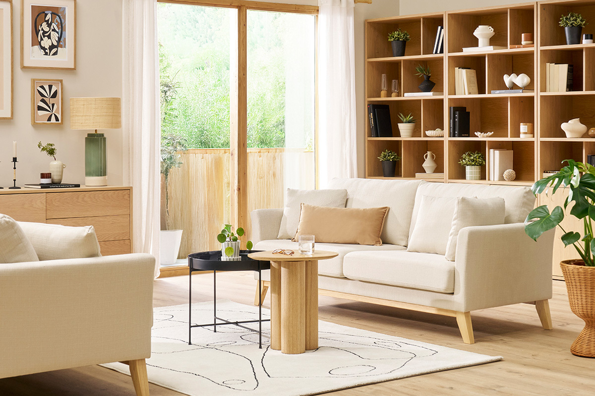 Canap� scandinave 3 places beige dans un salon lumineux avec table basse en bois.
