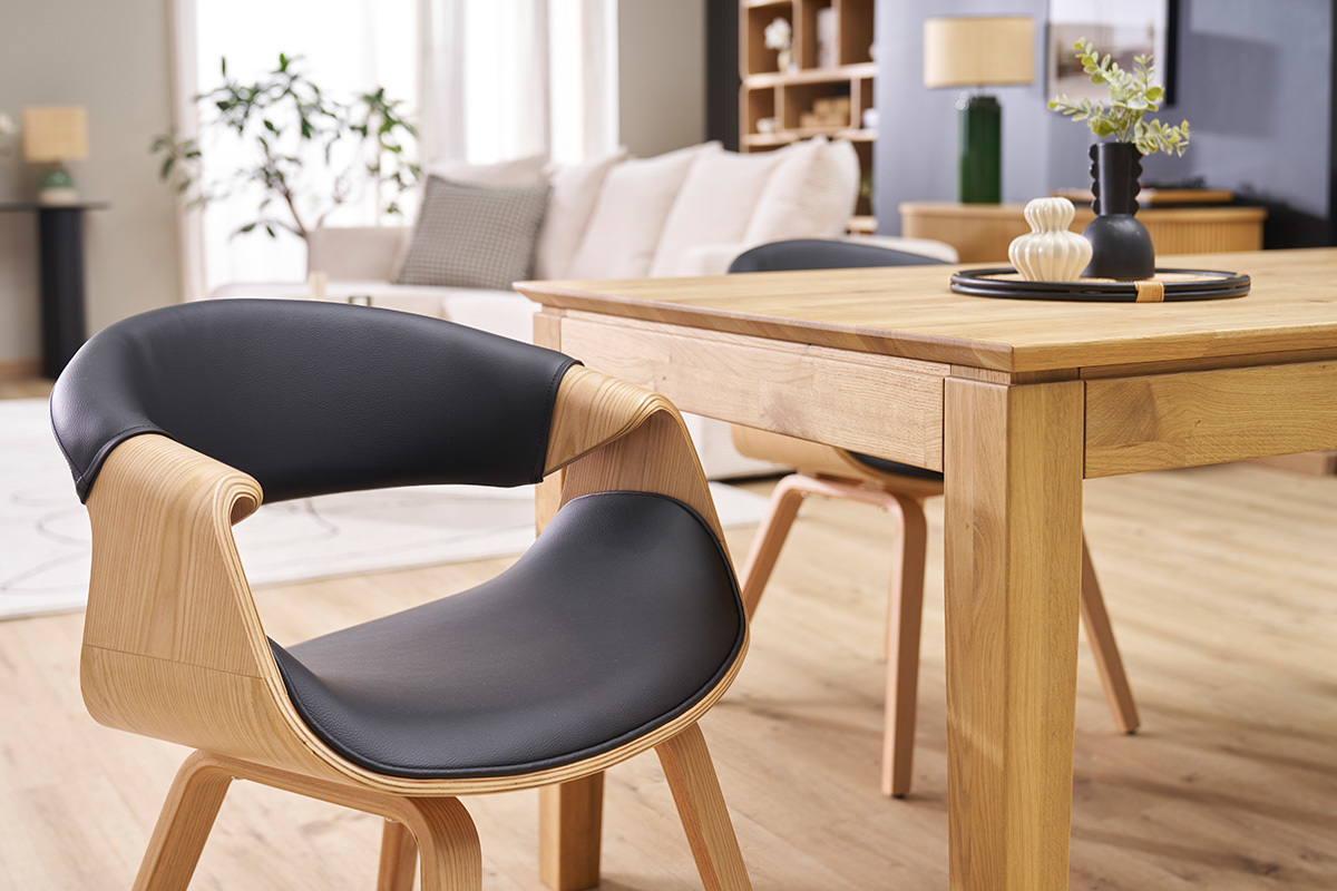 Chaise design ARAMIS en bois clair et cuir noir pr�s d'une table en bois, vue d'int�rieur.