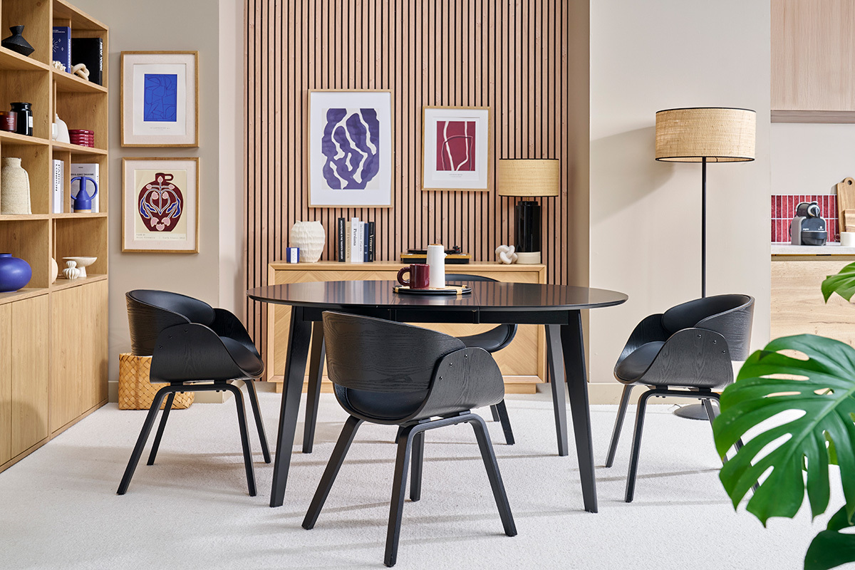 Chaises noires BENT autour d'une table noire dans un salon moderne avec des �tag�res et des cadres.