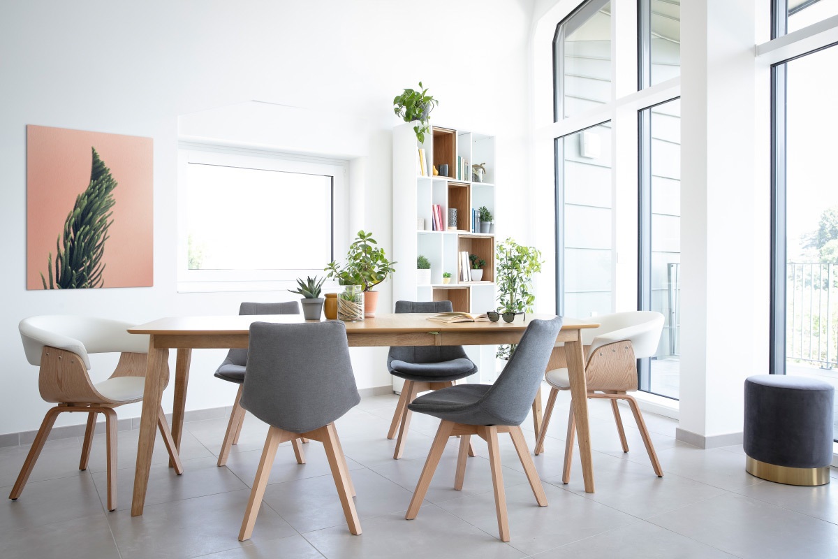 Chaise scandinave blanche et bois clair avec accoudoirs autour d'une table en bois dans une salle � manger lumineuse.