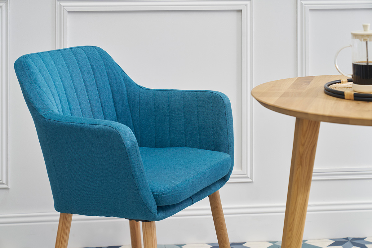 Chaise scandinave bleue ALEYNA en tissu, vue de c�t�, avec une table en bois.