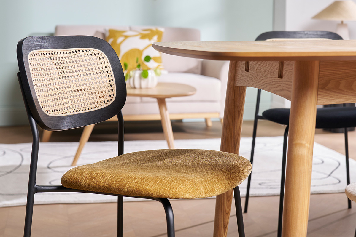 Chaise design en tissu bronze et cannage rotin, vue de c�t� pr�s d'une table en bois.