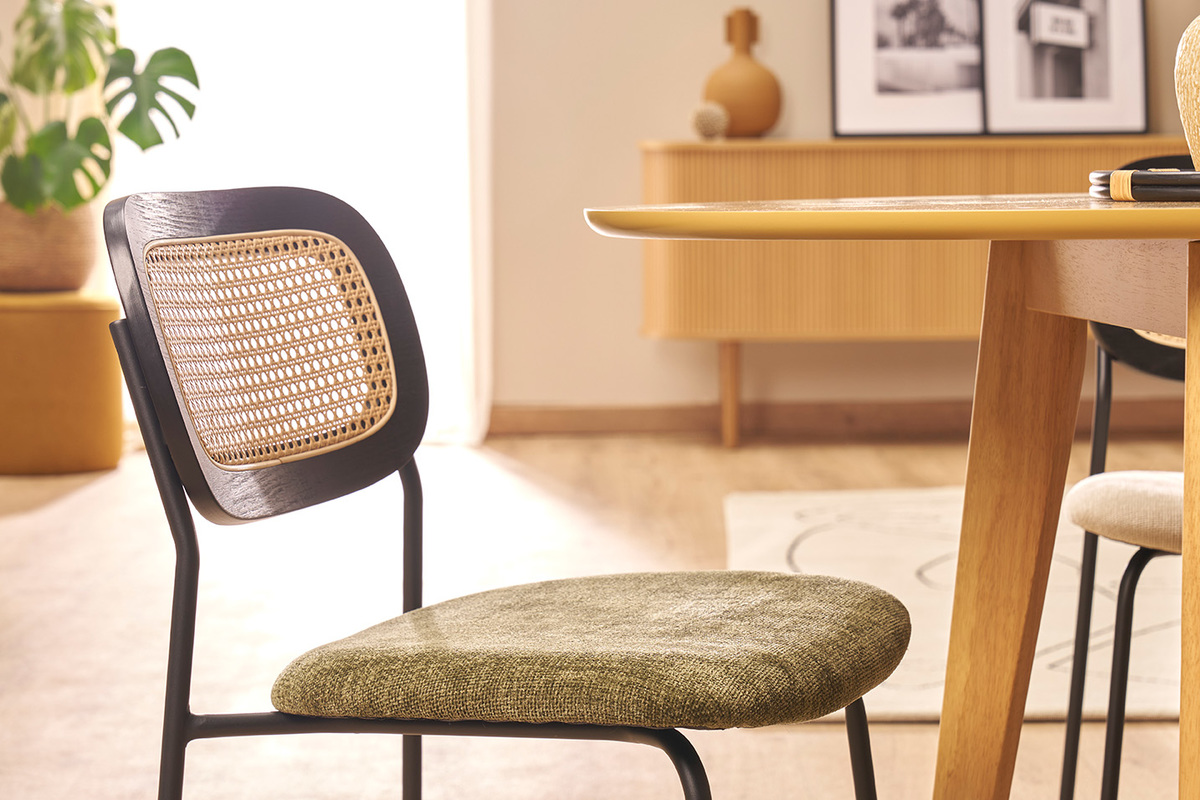 Chaise design en tissu vert kaki avec dossier en cannage rotin, vue de c�t�, � c�t� d'une table en bois.