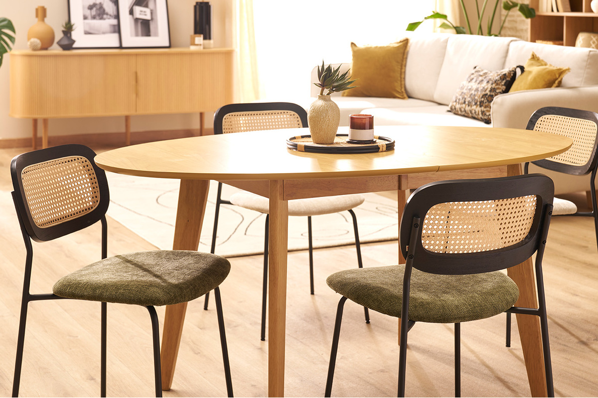 Chaises design en tissu vert kaki avec dossier en cannage autour d'une table en bois dans un salon lumineux.