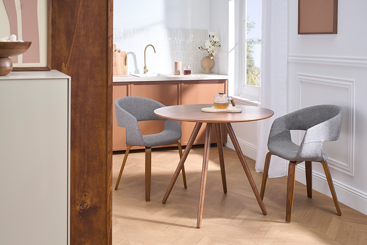 Chaises design gris en tissu avec pieds en bois fonc� autour d'une table ronde dans un int�rieur moderne.