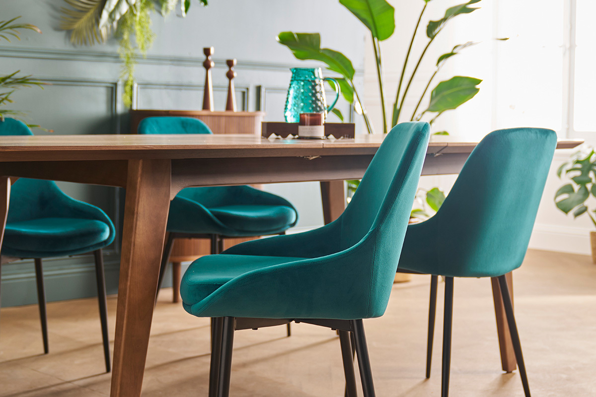 Chaises en velours bleu p�trole et m�tal noir autour d'une table en bois, vue lat�rale.