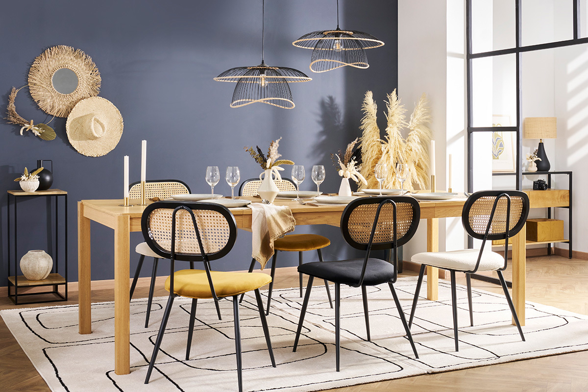 Chaises design en velours et rotin autour d'une table en bois clair.