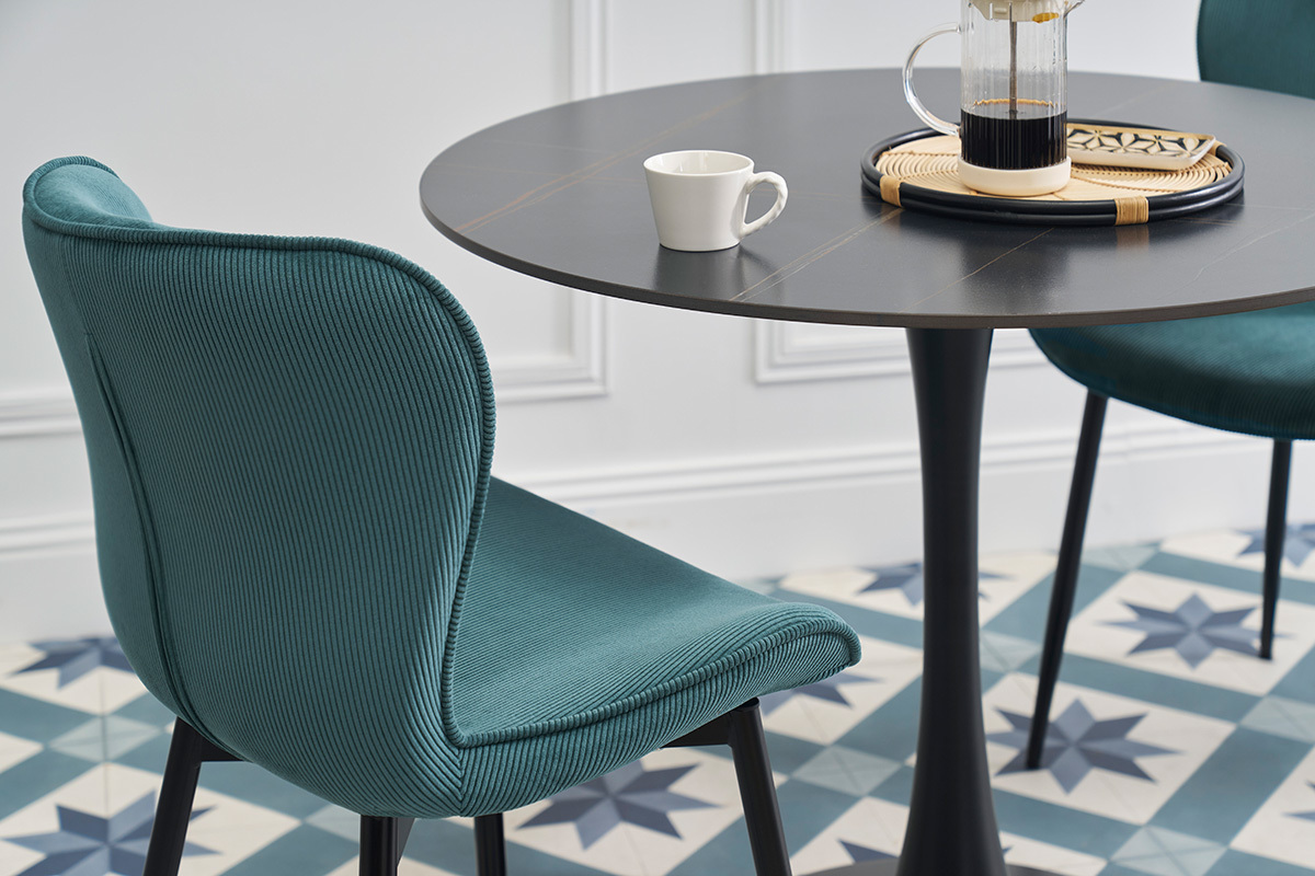 Chaise design en velours c�tel� bleu canard � c�t� d'une table noire.