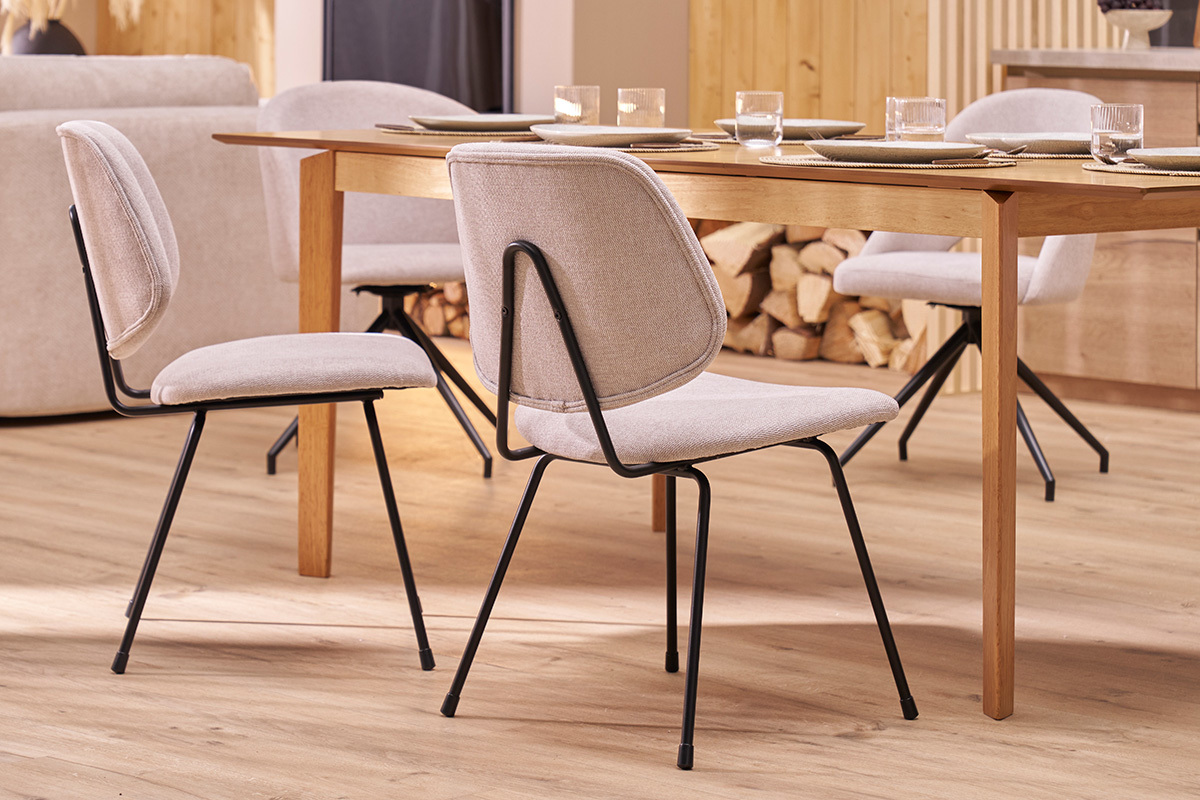 Chaises design en tissu beige et m�tal noir, vue de face, autour d'une table en bois.