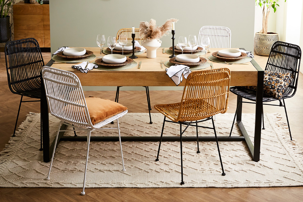Table � manger avec chaises en rotin et m�tal noir autour.