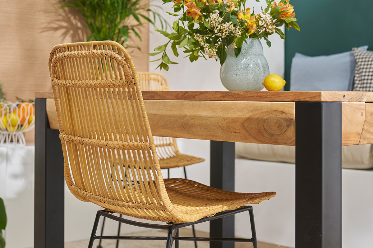 Chaise en rotin et m�tal noir MALACCA pr�s d'une table en bois, vue de dos.