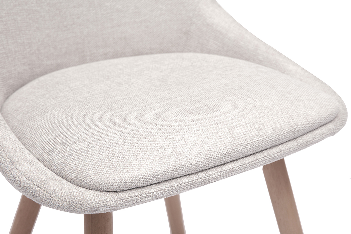 Gros plan sur l'assise rembourr�e d'une chaise en tissu effet velours beige et pieds en bois clair.