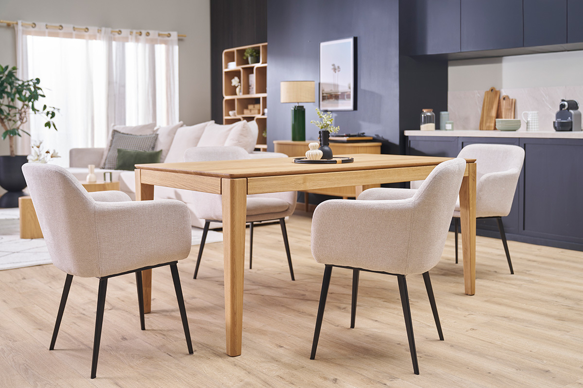 Quatre chaises en tissu beige et m�tal noir autour d'une table en bois, vue d'angle dans un salon.