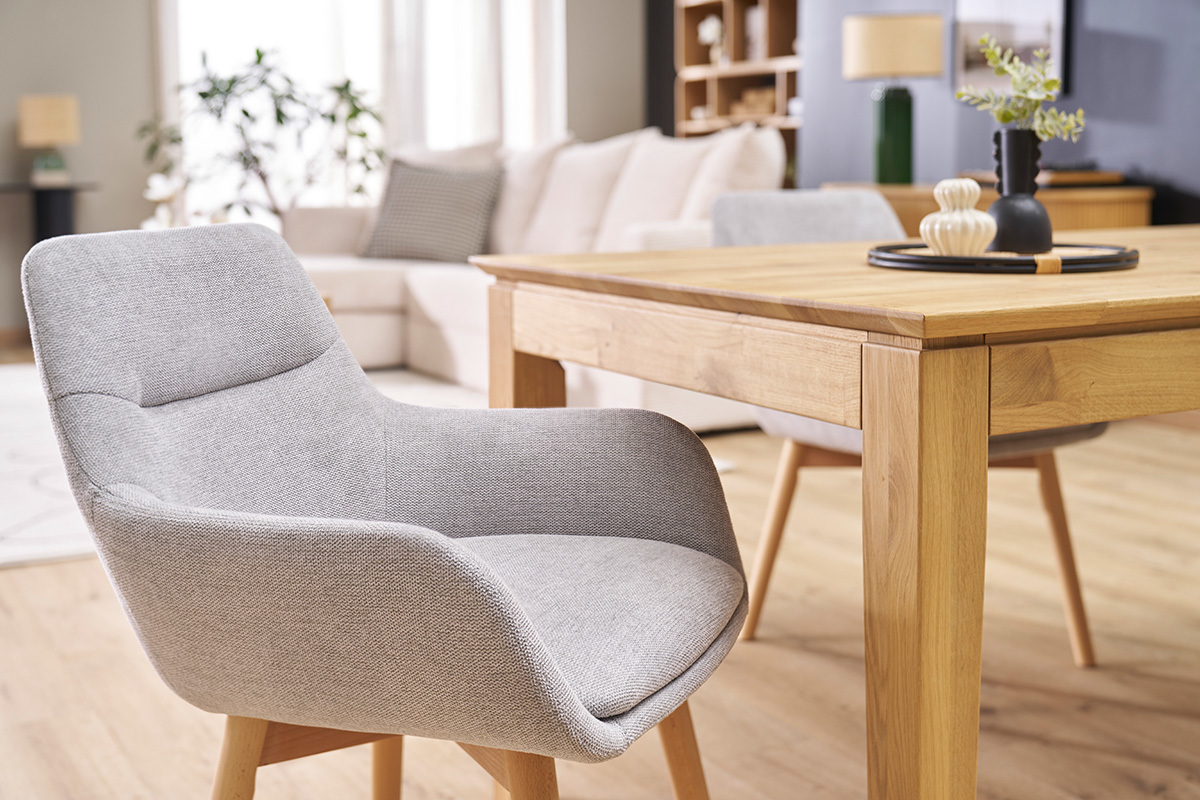Chaise en tissu gris clair et bois clair, vue de c�t�, � c�t� d'une table en bois.