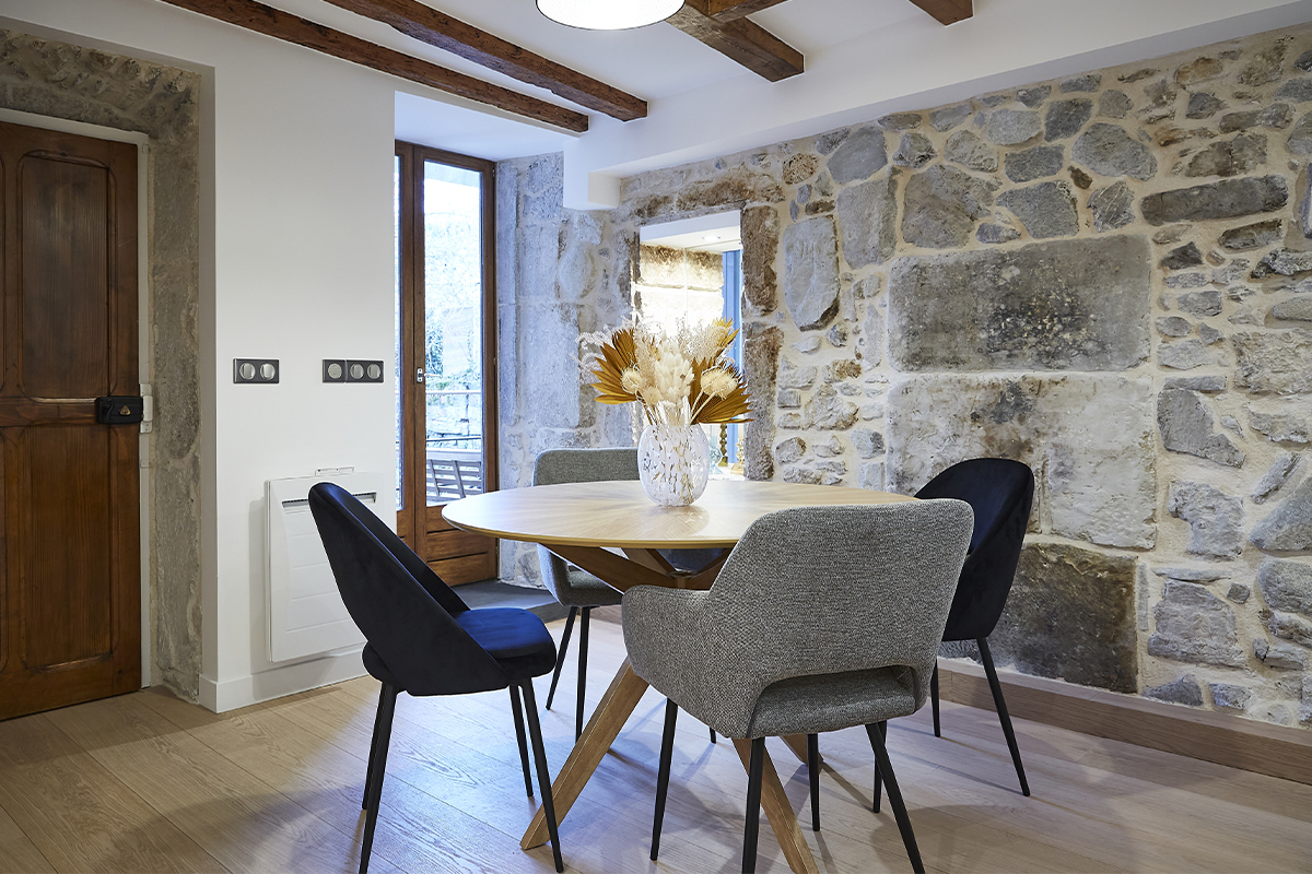 Salle � manger avec chaises grises en tissu effet velours autour d'une table ronde.