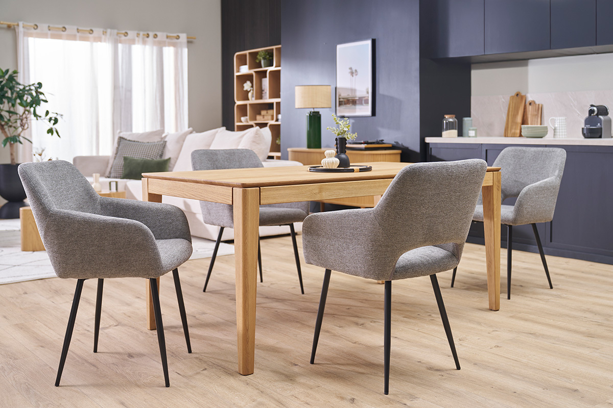 Quatre chaises LAURETTE en tissu effet velours gris et m�tal noir autour d'une table en bois dans un salon.
