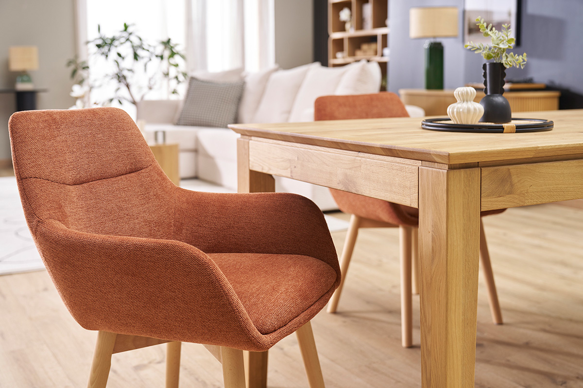 Chaises en tissu terre br�l�e avec pieds en bois clair autour d'une table en bois dans un salon.