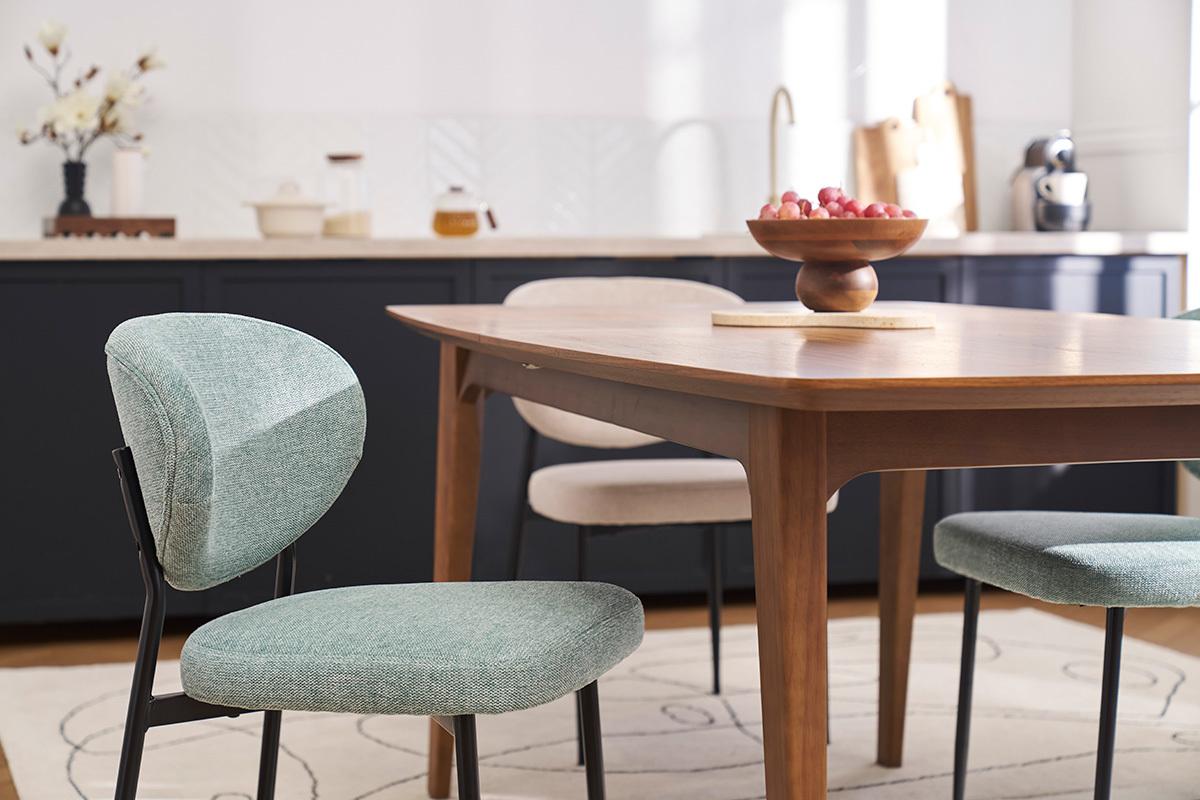 Chaises effet velours vert c�ladon avec pi�tement m�tal noir autour d'une table en bois.