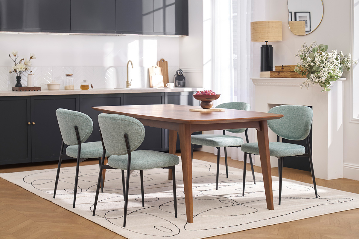 Quatre chaises BREKA en tissu vert c�ladon autour d'une table en bois dans une salle � manger moderne.