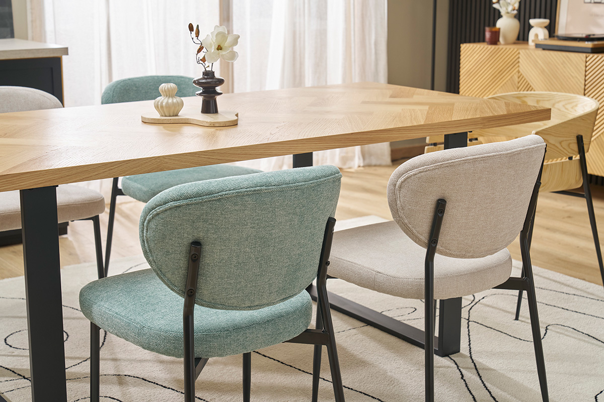Chaises BREKA en tissu c�ladon et m�tal noir autour d'une table en bois.