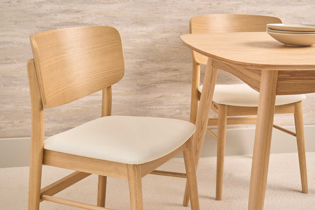 Chaises scandinaves blanches et bois clair, vue rapproch�e, avec une table en bois en arri�re-plan.