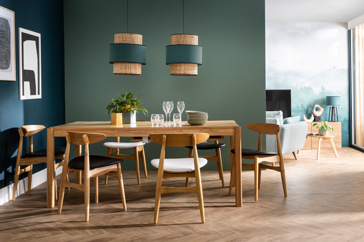 Salle � manger avec chaises scandinaves en bois clair et noir, autour d'une table en bois.