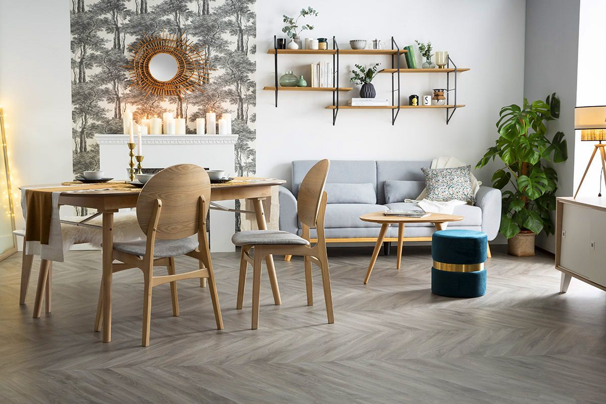 Chaises scandinaves en bois clair et tissu gris pr�s d'une table ronde.