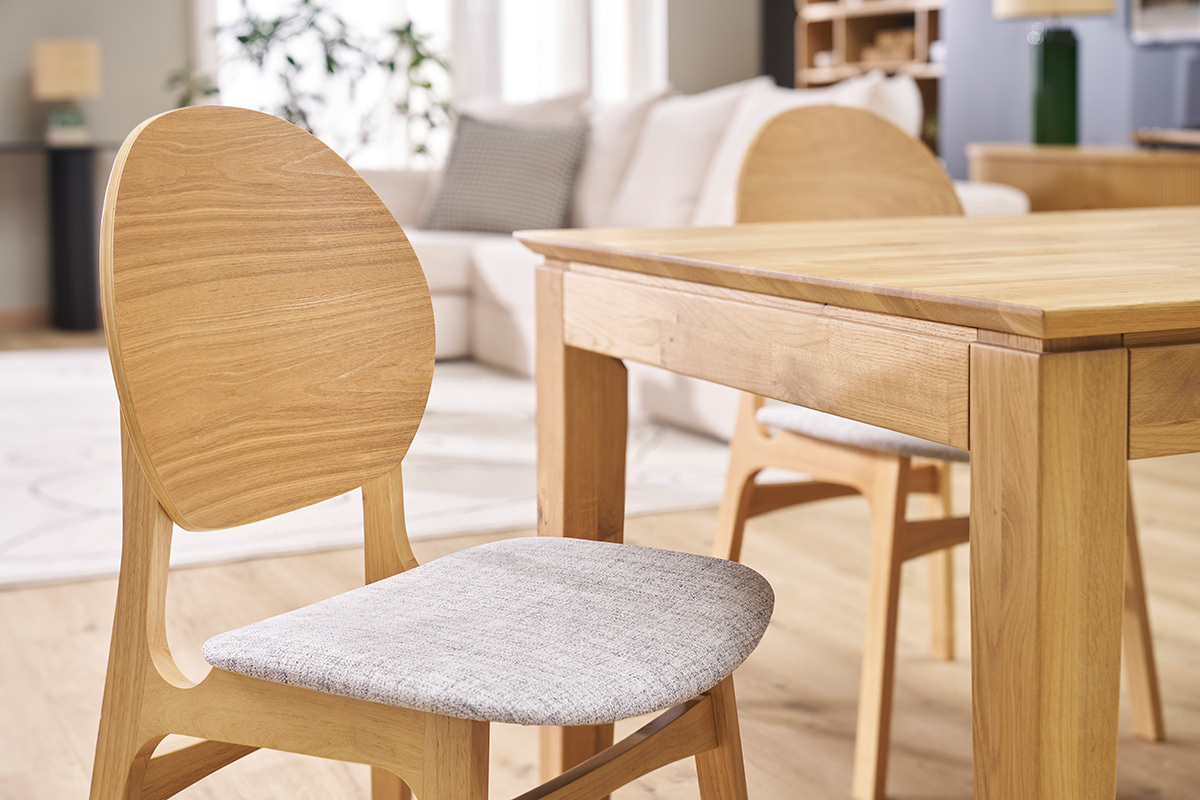 Chaises scandinaves en bois clair et tissu gris devant une table en bois, vue de c�t�.