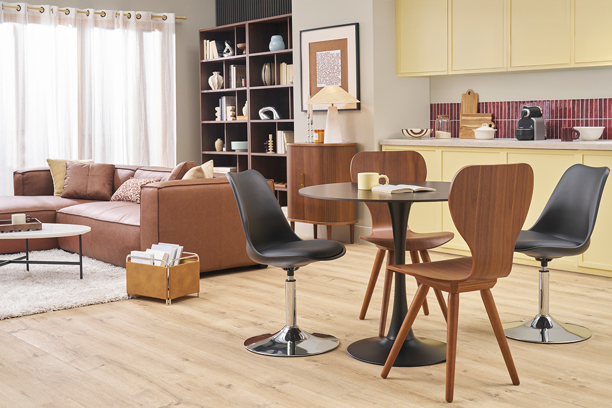 Chaises vintage bois fonc� noyer autour d'une table ronde noire dans un salon moderne.