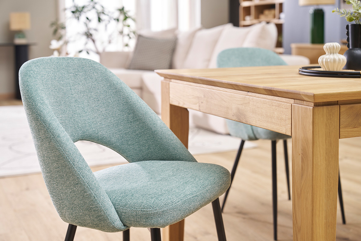 Chaises vintage vert c�ladon avec pieds noirs, pr�s d'une table en bois, dans un salon moderne.