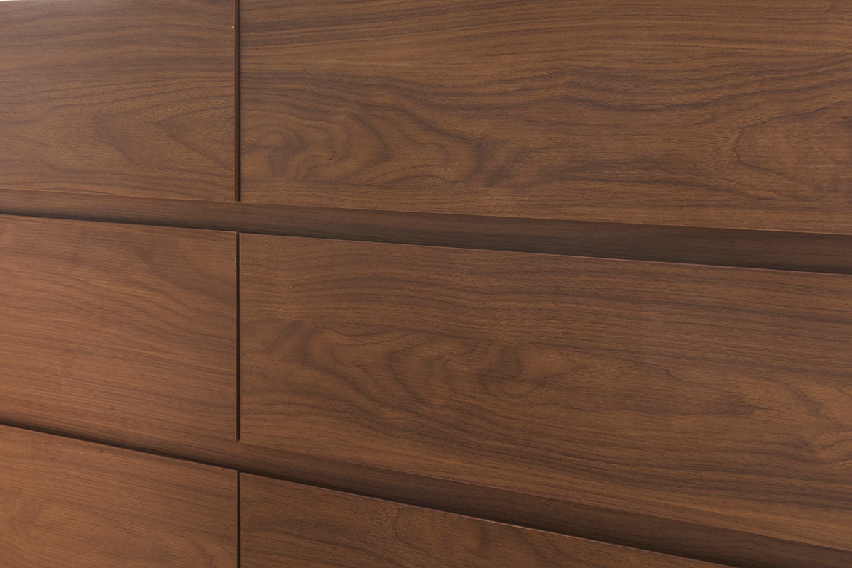 Zoom sur une commode en bois fonc� noyer, montrant le grain du bois et deux tiroirs ferm�s.