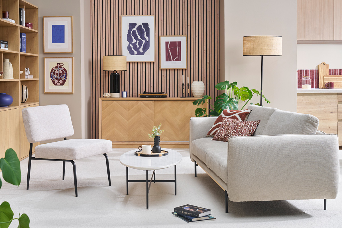 Fauteuil en tissu chenille beige et m�tal noir, vue de c�t� dans un salon.